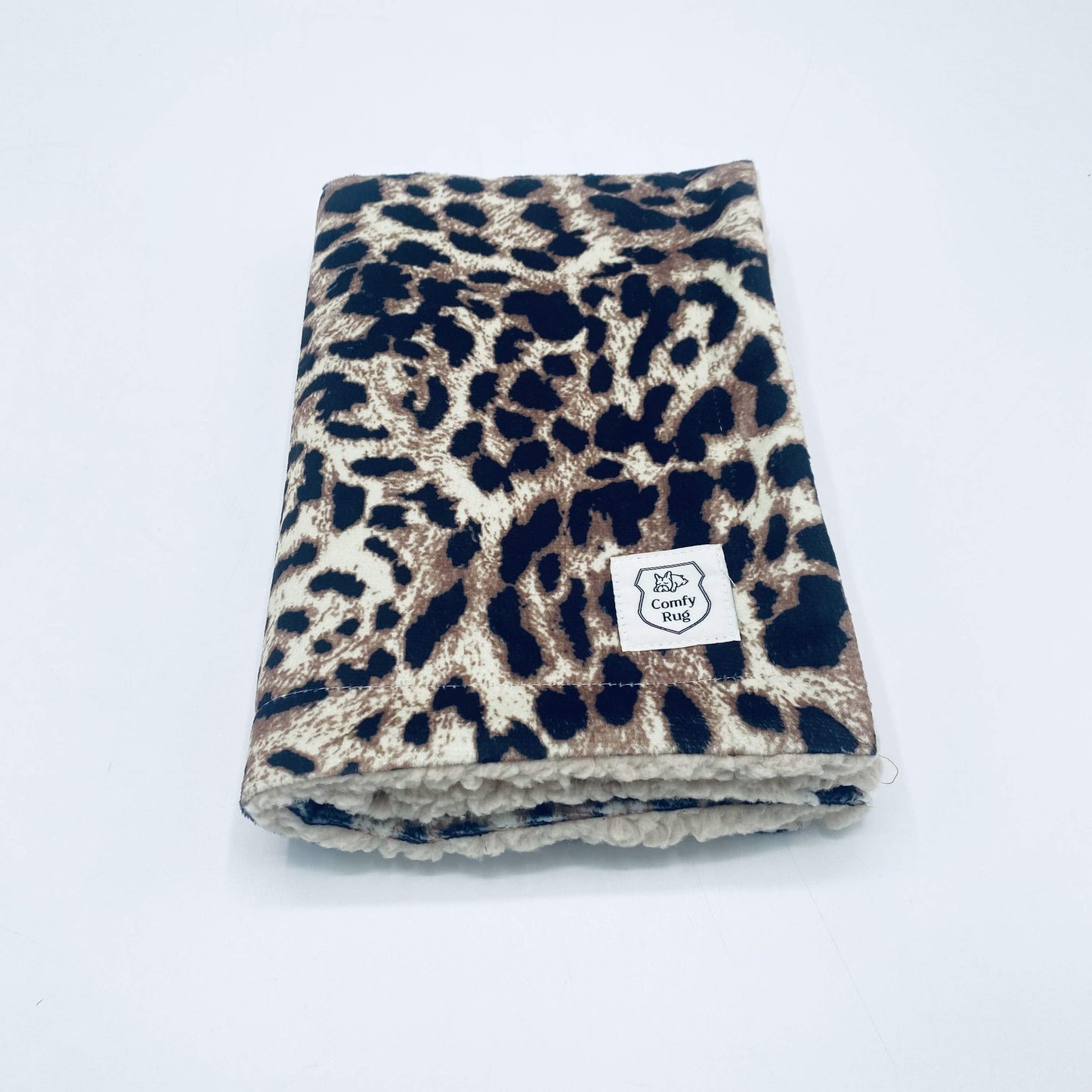 ComfyRug Cheetah er et vanntett og varmt hundeteppe . Teppet har et mønster av leopard på ene siden og sherpa på andre siden. I det ene hjørnet er det en logo.