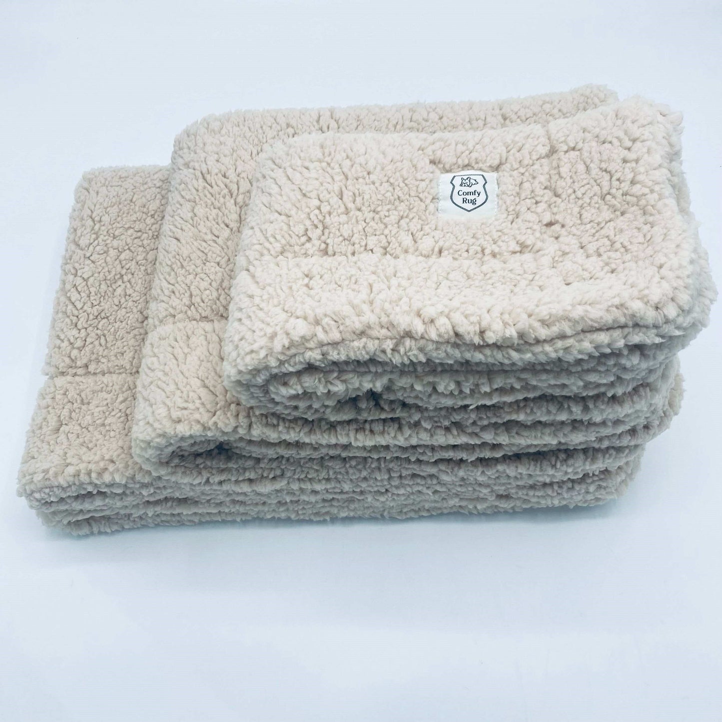 ComfyRug Teddy hundeteppe - Hundetepper. 3 beige hundetepper som ligger oppå hverandre. Teppene er i sherpa stoff og har logo i hjørnet.